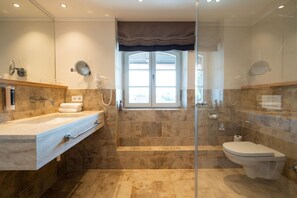 A modern bathroom with a glass shower enclosure, a large window, and a separate toilet area. - Hotel Gasthof Alte Post Holzkirchen (Holzkirchen)