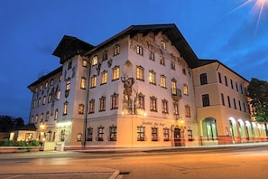 Ein historisches Gebäude mit zahlreichen Fenstern, einem zentralen Eingang und einem Schild mit der Aufschrift 'Gasthof Allee Post'.