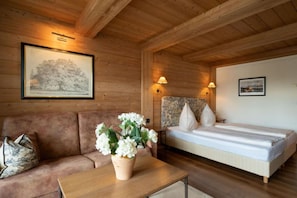 Ein Holzblockhaus im Inneren mit einem Bett, einer Couch, einem Tisch und einem gerahmten Bild an der Wand.