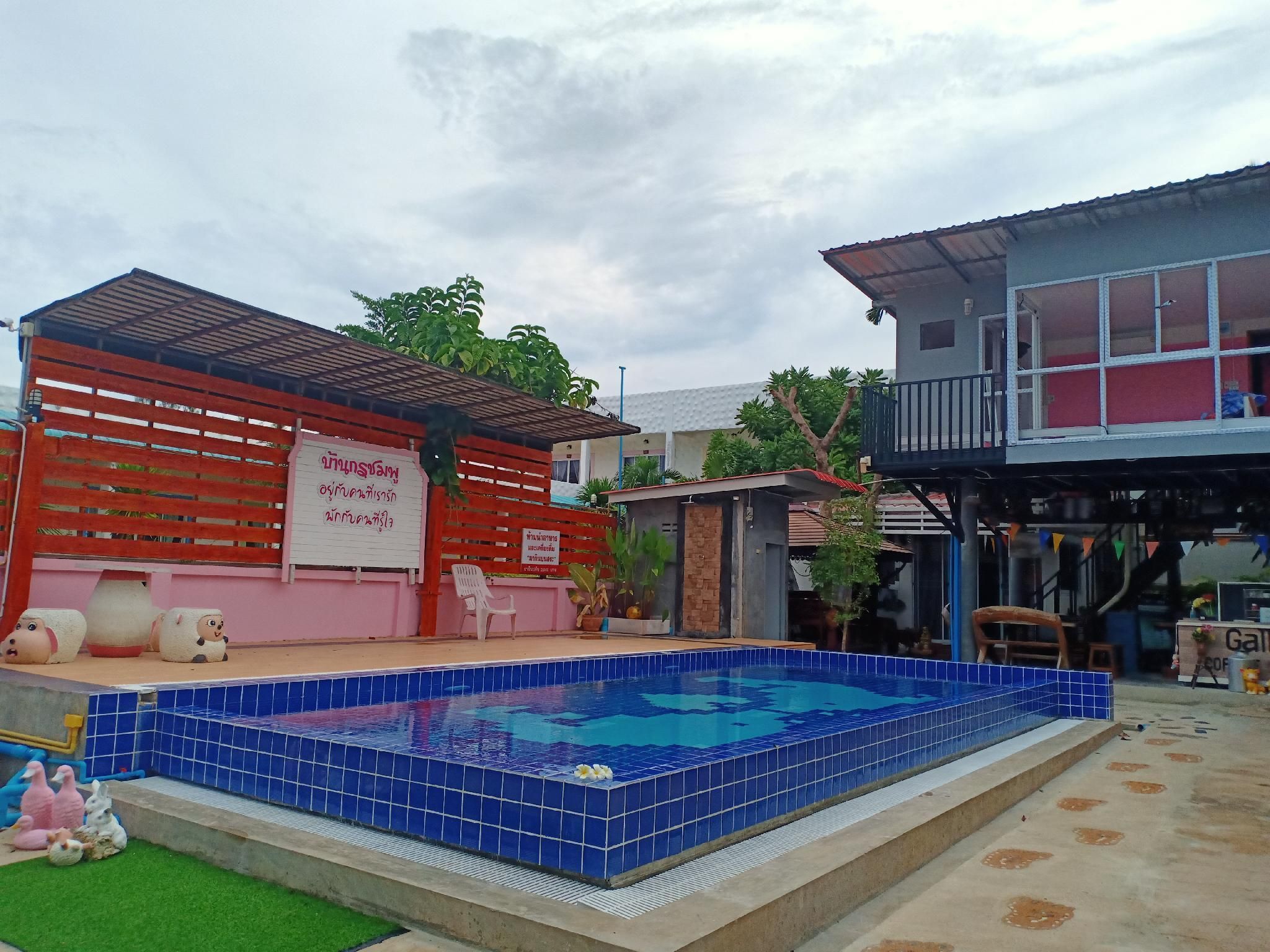 A swimming pool with blue tiles, a red fence, and a small building with a sign.