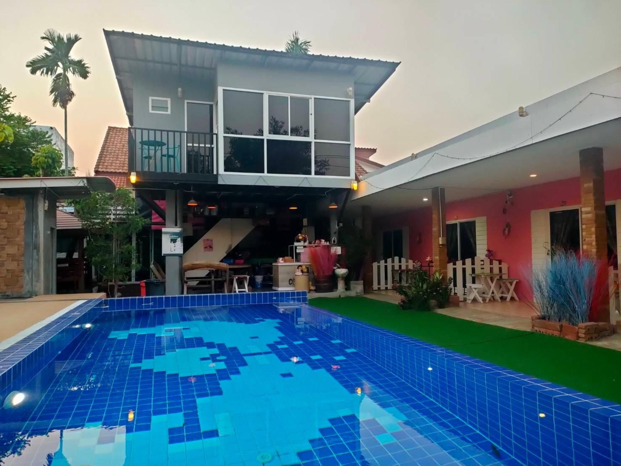 A two-story building with a swimming pool, a covered patio, and a fenced outdoor area.