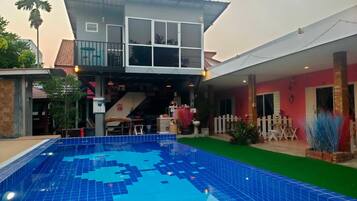 A two-story building with a swimming pool, a covered patio, and a fenced outdoor area.