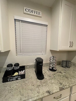 A kitchen with a coffee station, a Keurig coffee maker, a coffee mug rack, and a sign that reads 'COFFEE'. - The Heights Retreat - Casa Azul at Cottage Grove (Houston)