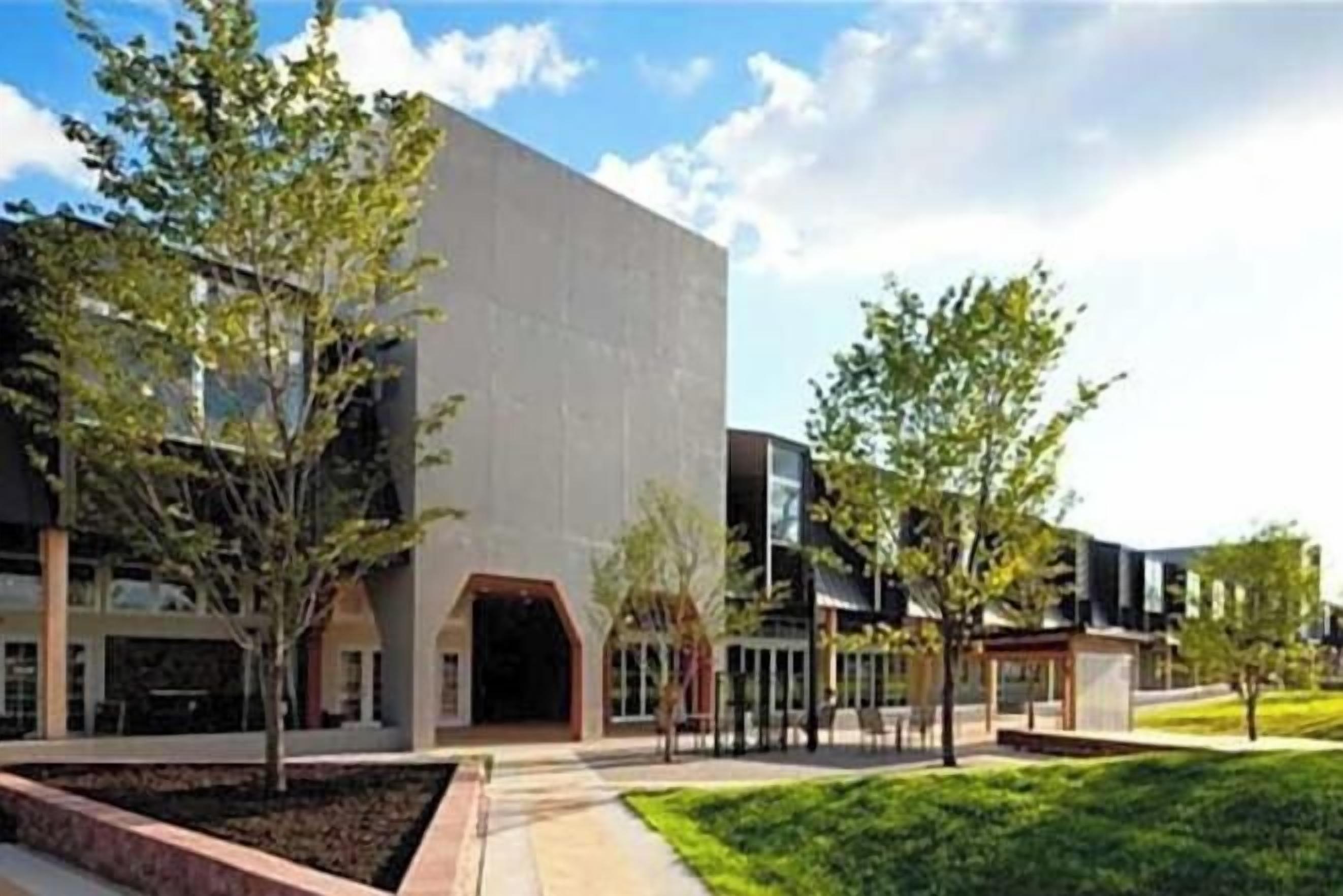 A modern building with a flat facade, a central entrance, and a small adjacent structure.
