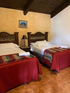 Une chambre avec deux lits, une table de chevet, une lampe et un tableau encadré au mur.
