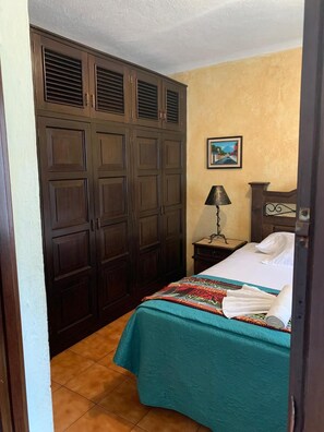 Une chambre à coucher avec un lit, une table de chevet, une lampe, une armoire et un tableau au mur.