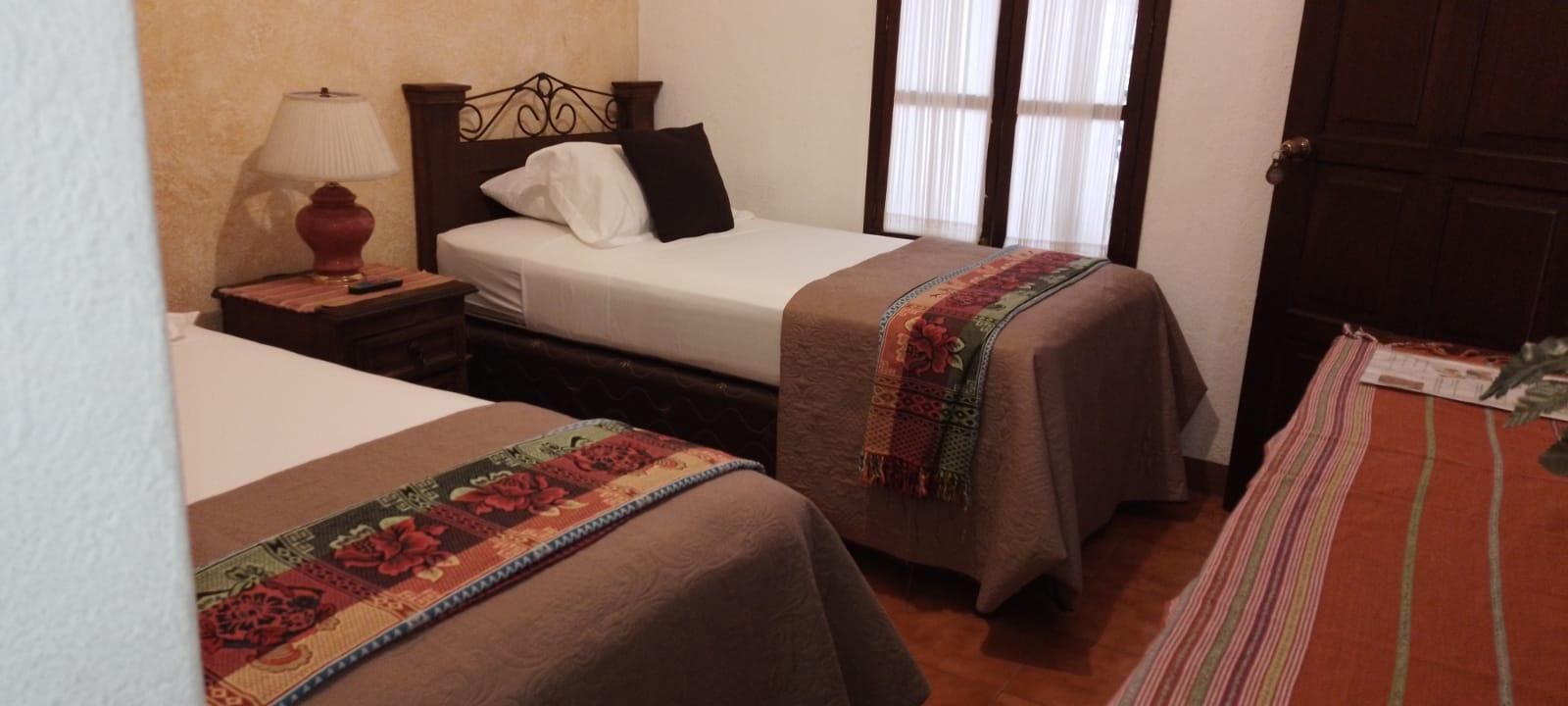 Ein Hotelzimmer mit zwei Betten, einem Nachttisch mit Lampe und einer Tür.