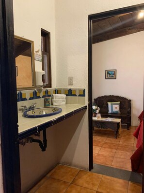 Une salle de bain avec un lavabo, un miroir et un mur recouvert de carreaux.