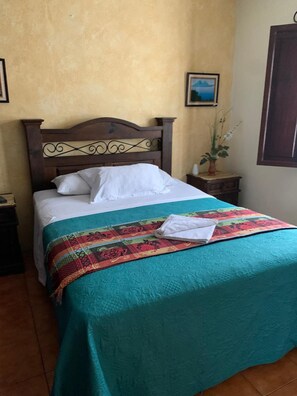 Un lit avec une tête de lit en bois, une couvre-lit turquoise et une couverture colorée.