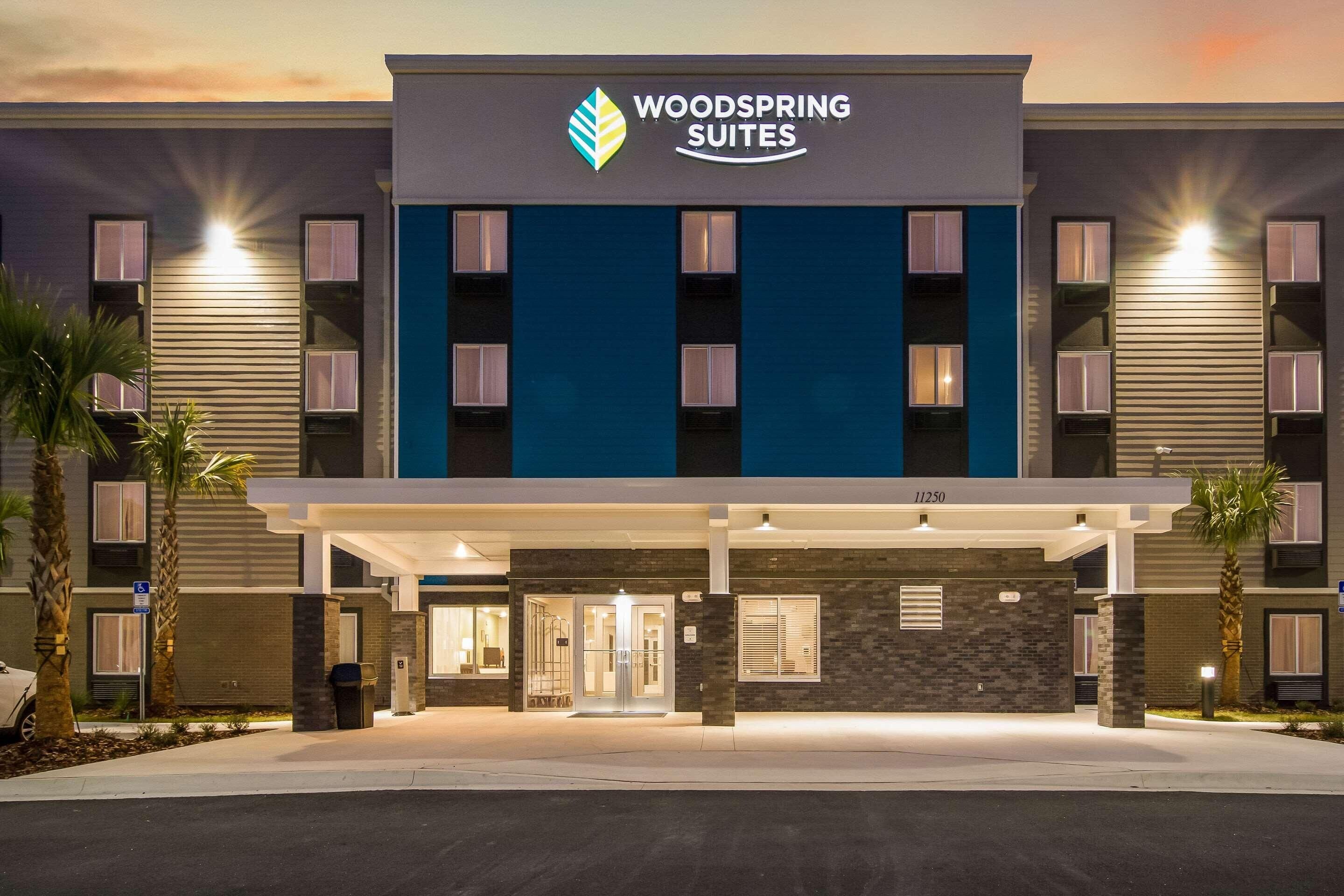 Een hotel met een moderne gevel, een opvallend logo en een goed verlichte ingang.