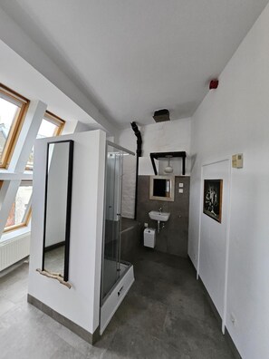 Un baño moderno con cabina de ducha de vidrio, un lavamanos blanco y un espejo.