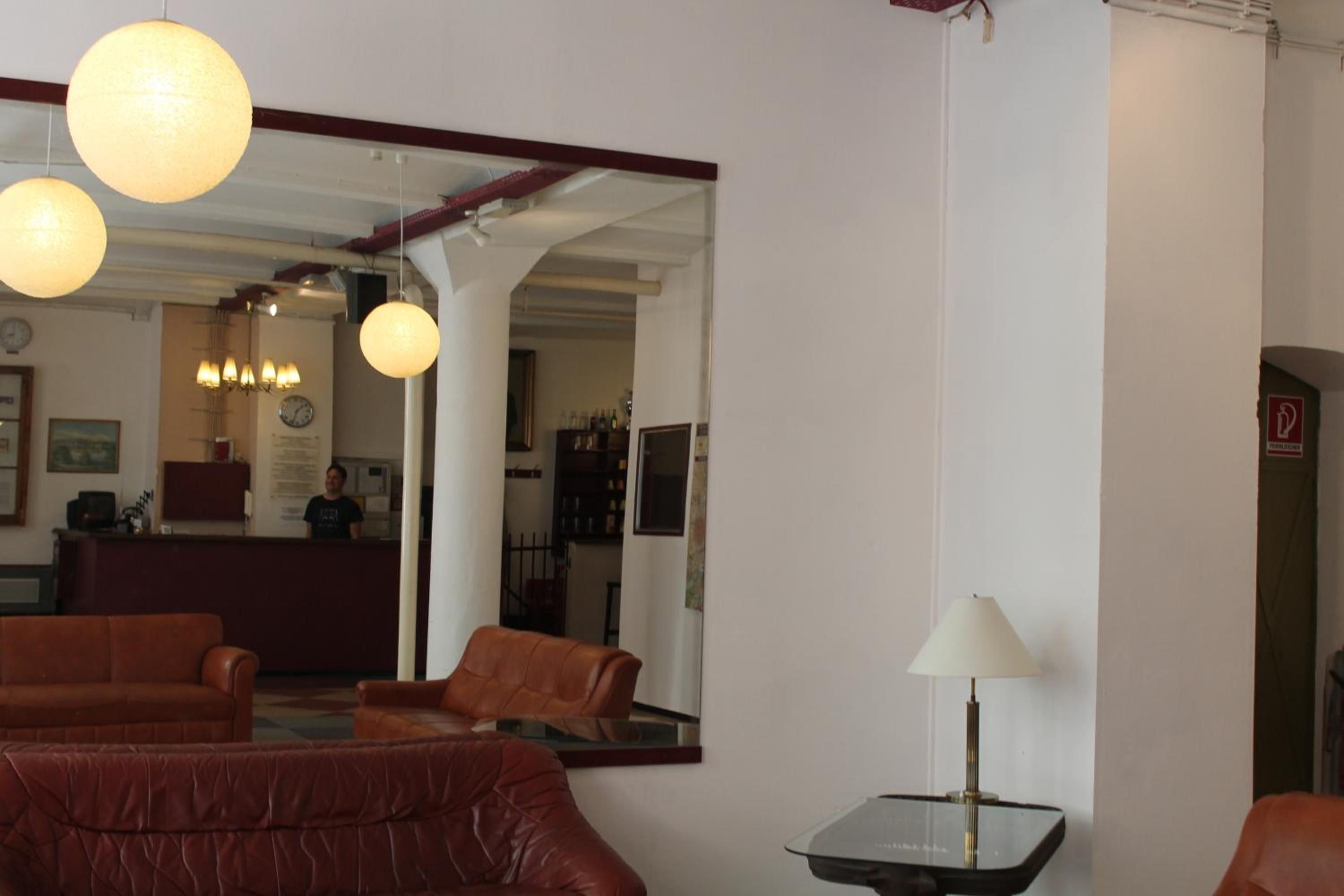 A hotel lobby with leather sofas, a reception desk, and a mirror reflecting the interior.