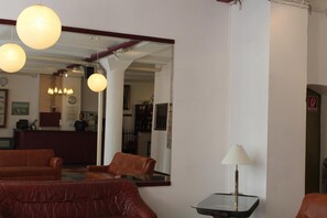 Un hall d’hôtel avec des canapés en cuir, un comptoir d’accueil et un miroir qui reflète l’intérieur.