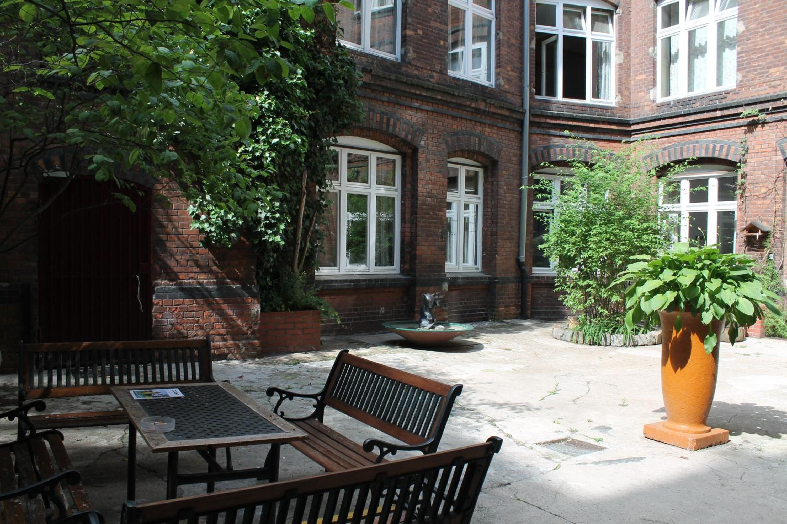 A courtyard with a brick building, a fountain, and outdoor seating.