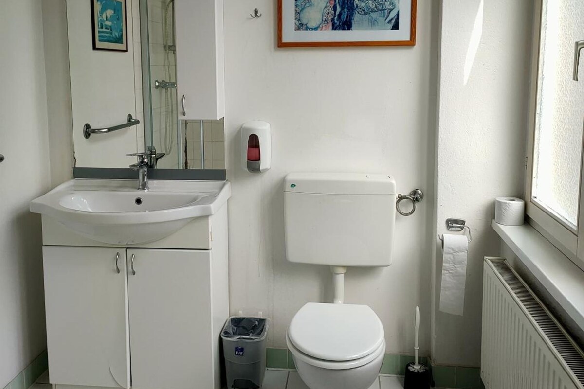 Une salle de bain avec un lavabo, des toilettes et un tableau abstrait encadré accroché au mur.