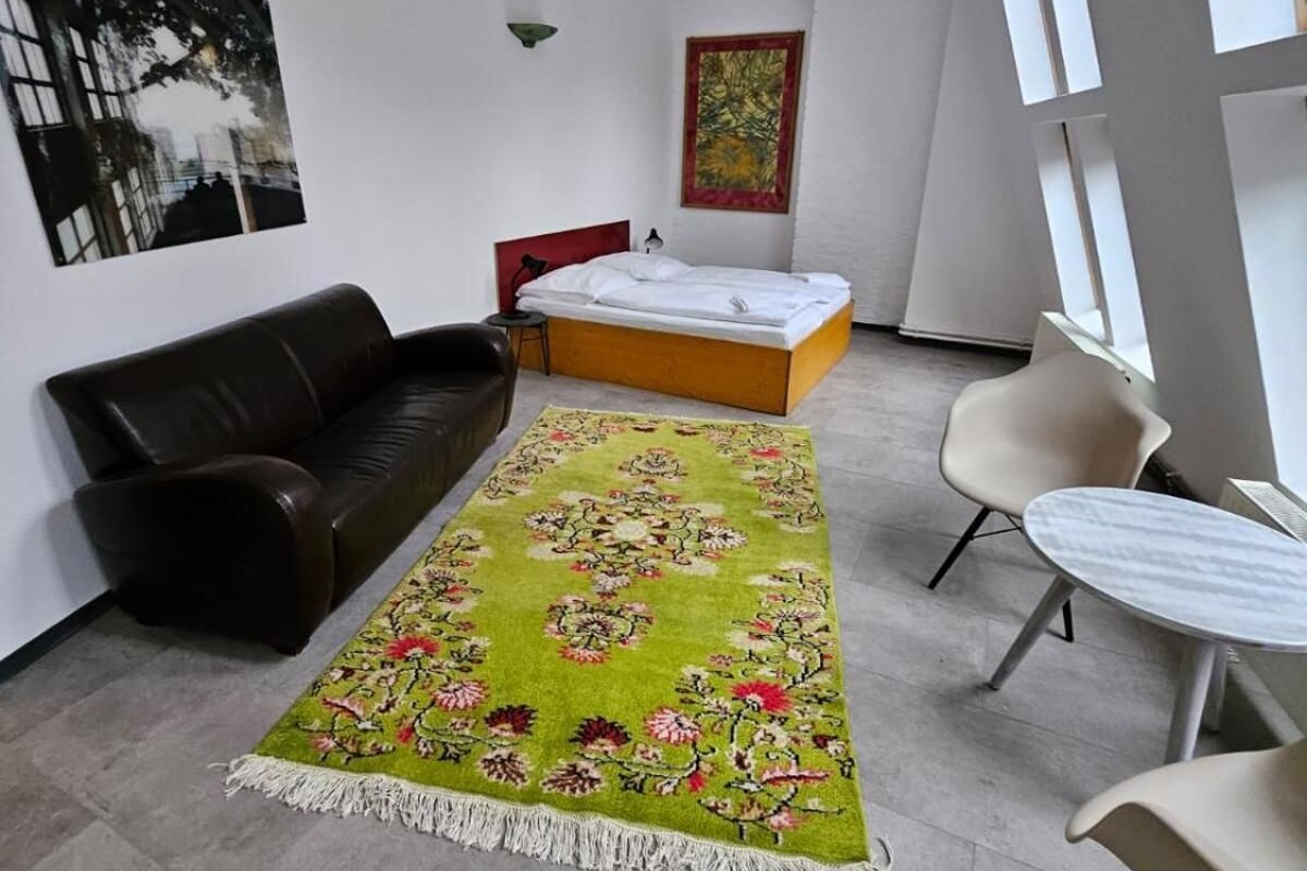Une chambre moderne comprenant un lit, un canapé, une table à manger et un grand tapis.
