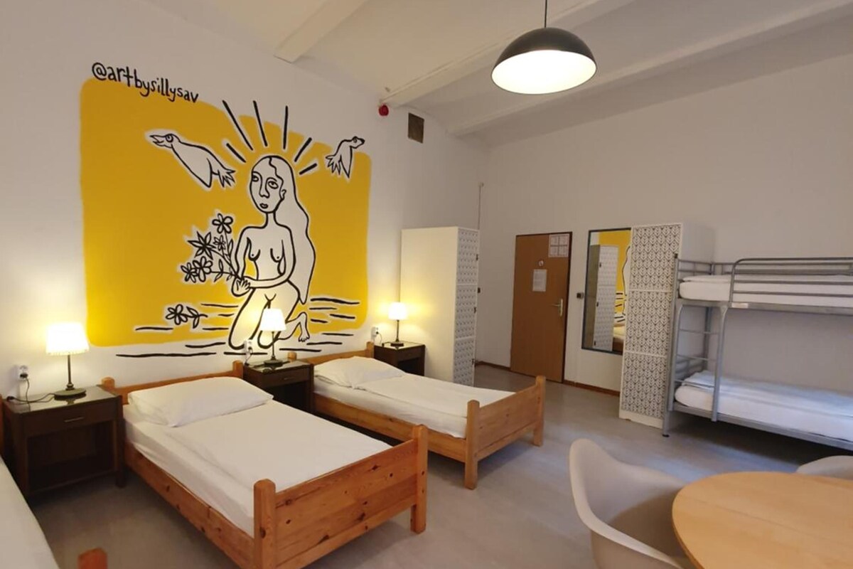 Une pièce avec des lits superposés, une table à manger et une fresque murale.