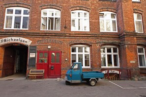 Ein Backsteinhaus mit einem Schild, auf dem 'P.Michaelsen' steht, und ein blauer Lkw vor der Fassade.