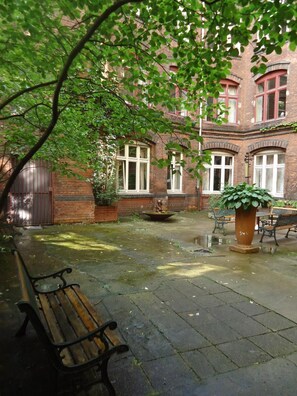 Ein Innenhof mit einer Bank, einem Pflanzkübel und einem Brunnen.