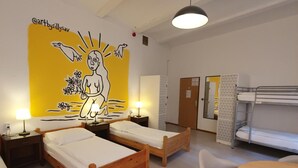 A room with bunk beds, a dining table, and a mural on the wall.