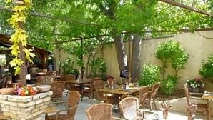 An outdoor patio area with wicker furniture, stone pillars, and potted plants. - Auberge De La Table Ronde (Vinon-sur-Verdon)