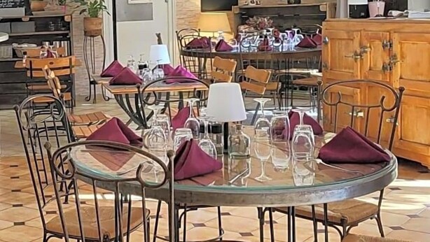 A restaurant with round tables, chairs, and a brick wall. - Auberge De La Table Ronde (Vinon-sur-Verdon)