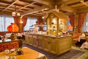 A cozy dining area with wooden beams, a central island with a clock, and a variety of breakfast items. - Hotel Zum Lv Wen Unteres Wirtshaus (Titisee-Neustadt)