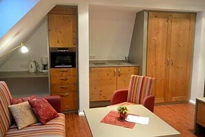 A compact room with a kitchenette, a dining table, and a sofa. - Hotel Zum Lv Wen Unteres Wirtshaus (Titisee-Neustadt)