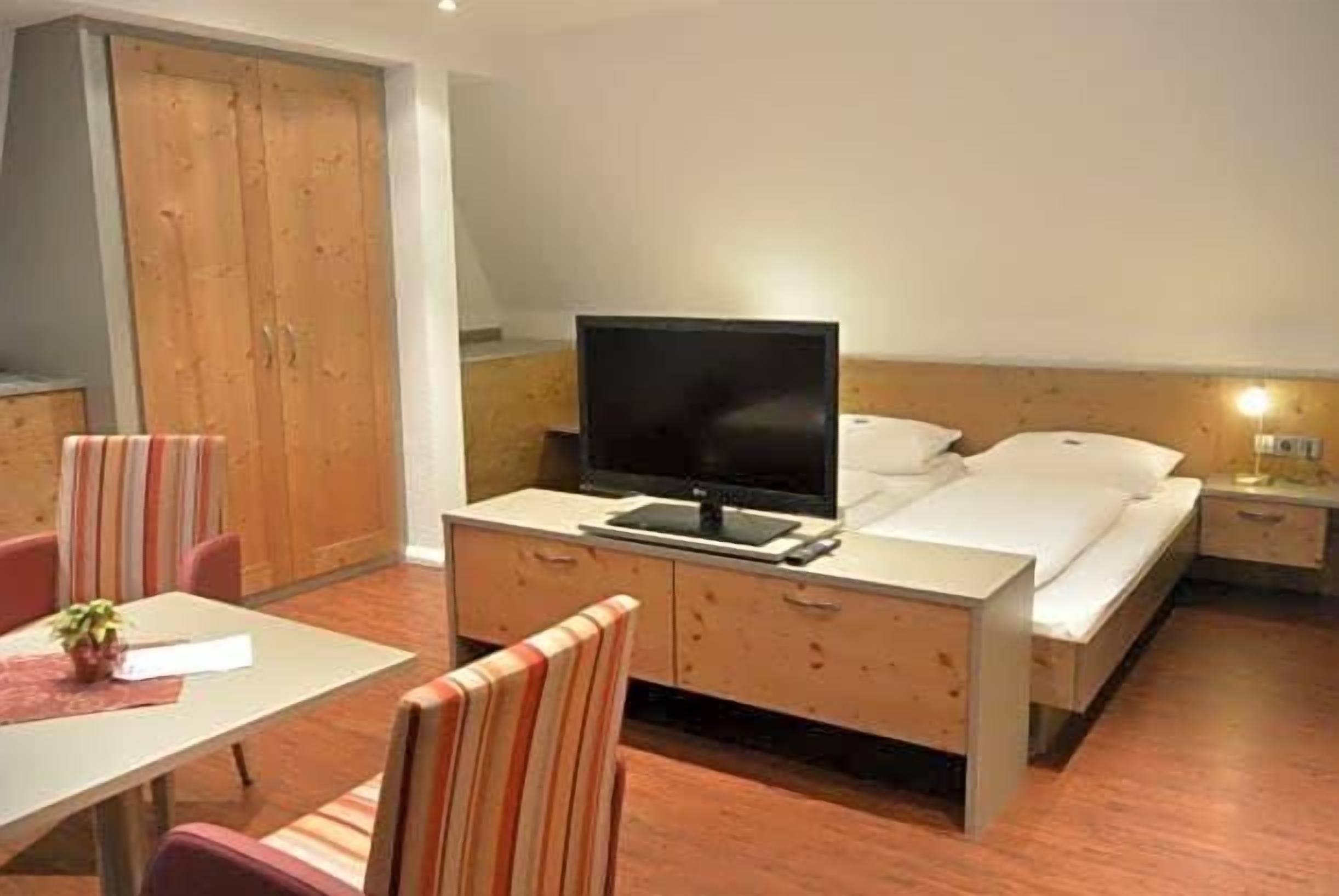 Ein Hotelzimmer mit Bett, Fernseher, Schreibtisch und Stuhl.