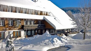A snow-covered building with a sloped roof, a visible entrance, and a snow-covered ground. - Hotel Zum Lv Wen Unteres Wirtshaus (Titisee-Neustadt)