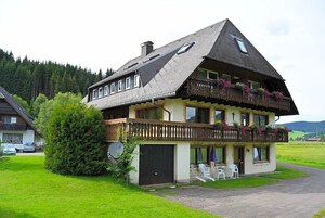 Ein zweistöckiges Gebäude mit Balkon, Satellitenschüssel und einer kleinen Außen-Sitzgelegenheit.