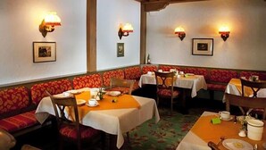 Un restaurant avec des banquettes et des tables, un éclairage mural et des tableaux encadrés.
