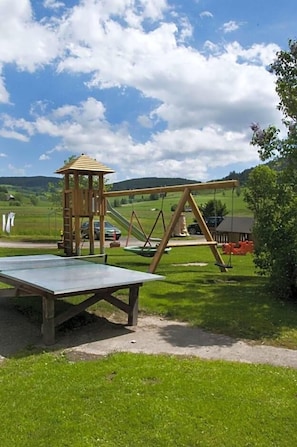 Une aire de jeux avec des balançoires et une structure d’escalade.