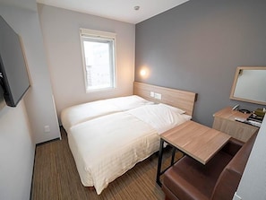 Een hotelkamer met een bed, een bureau, een stoel, een televisie en een raam.