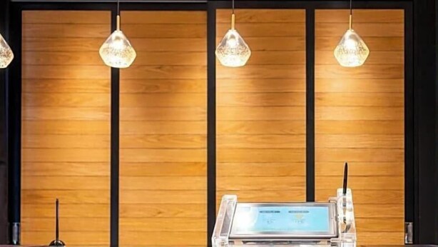 A reception desk with a digital screen, wooden panel background, and pendant lighting. - Super Hotel Okayama Station Higashiguchi (Okayama)