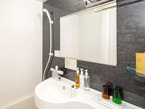 A bathroom with a white sink, a mirror, and a shower. There are toiletries on the sink. - Super Hotel Okayama Station Higashiguchi (Okayama)