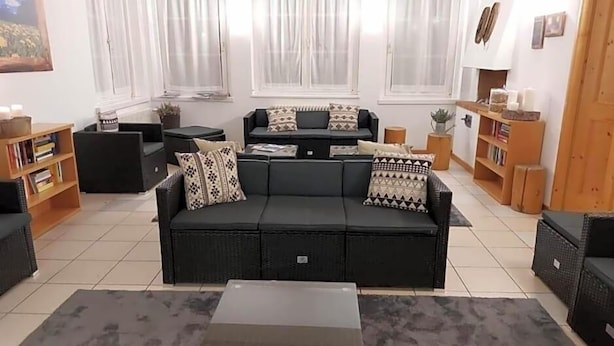 Ein Wohnzimmer mit einer Sofagarnitur, einem Couchtisch und einem Bücherregal.