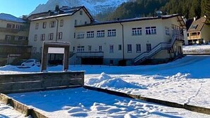 Ein Gebäude mit mehreren Fenstern und einer Treppe, umgeben von Schnee und Bergen.