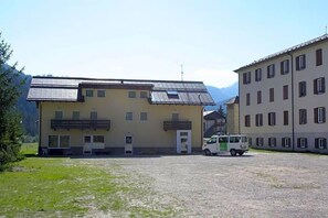 A building with a flat roof, a small balcony, and a van parked in front. - Soggiorno Dolomiti (Mazzin)
