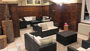Ein Zimmer mit Kamin, Holzvertäfelung und einer Sofagarnitur.
