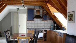 Eine Küche mit Holzausstattung, einer gefliesten Spritzschutzwand und einem Essbereich mit Tisch und Stühlen.
