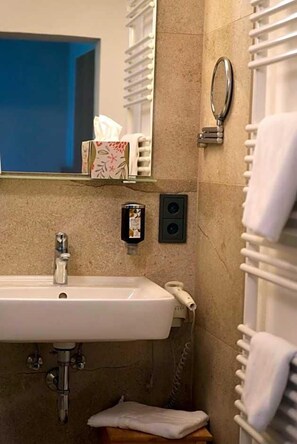 A bathroom with a sink, mirror, towel rack, and a wall-mounted telephone. - Gasthof Schweizerhof (Villingen-Schwenningen)