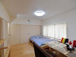 Un dormitorio con cama, una mesa, un armario y una ventana con cortinas.