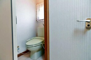 Une petite salle de bain compacte, équipée de toilettes, d’un lavabo et d’un rideau de douche.