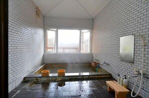 A small, tiled room with a window, a bench, and a shower area. - Stay In Otaki (Date)