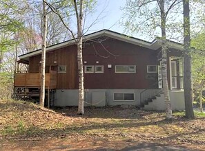 Une cabane à deux étages avec une terrasse en bois et un porche abrité.