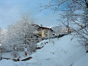 Paisagem coberta de neve com um edifício de telhado inclinado e várias janelas.