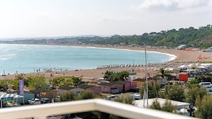 A coastal town with a beach, buildings, and a pier. - Hotel Scogliera (Numana)
