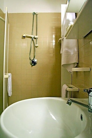 Een badkamer met een bad, een douchekop en een toilet.