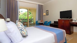 A hotel room with a bed, a desk, a television, and a balcony with chairs. - Stella Gardens Resort Spa Makadi Bay (Makadi Bay)